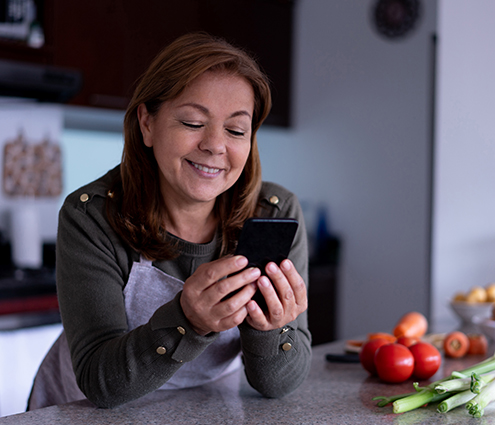 person smiling and texting her health coach in the kitchen