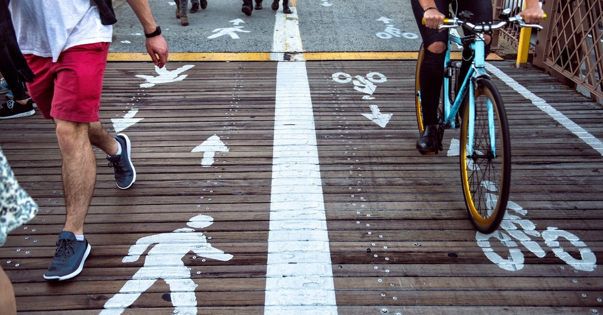 People walking and riding bike on pedestrian bridge.