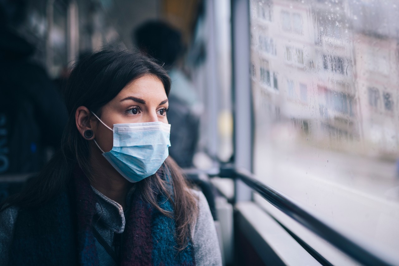 Young woman wearing protective face mask, she sitting in bus transportation in the city.
