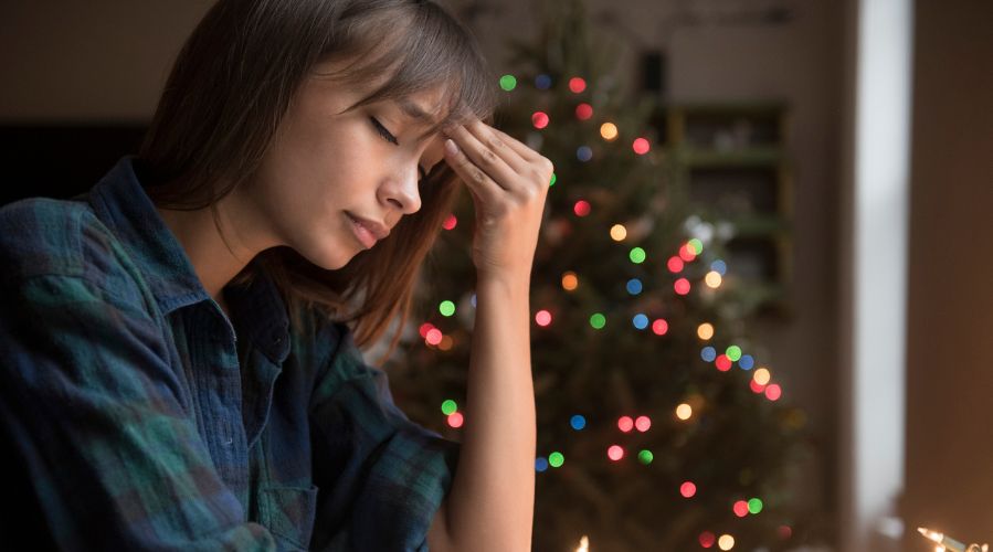 Mixed Race woman with headache near Christmas tree