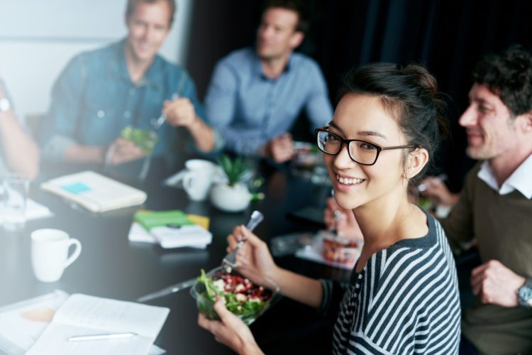 Portrait of a young office worker  eating lunch with coworkers at a boardroom table