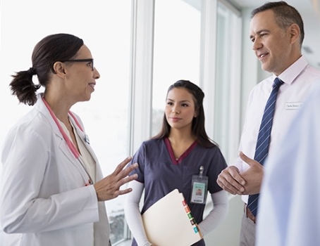 Young female doctor talking to male doctor and female assistant