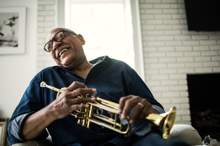 Senior man polishing trumpet at home