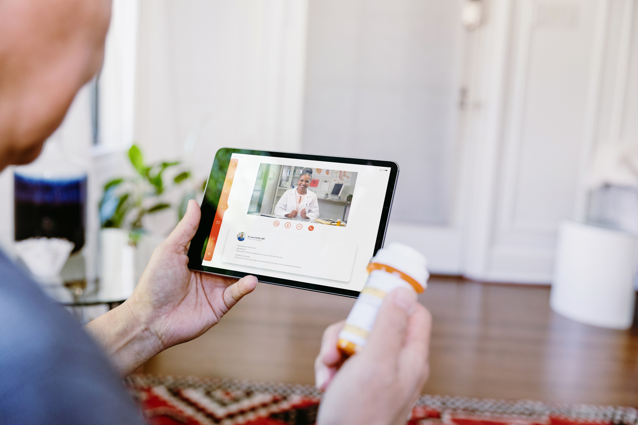 While holding a prescription medication container, an unrecognizable senior man video chats with a female doctor. The man is asking quesitons about his medication.