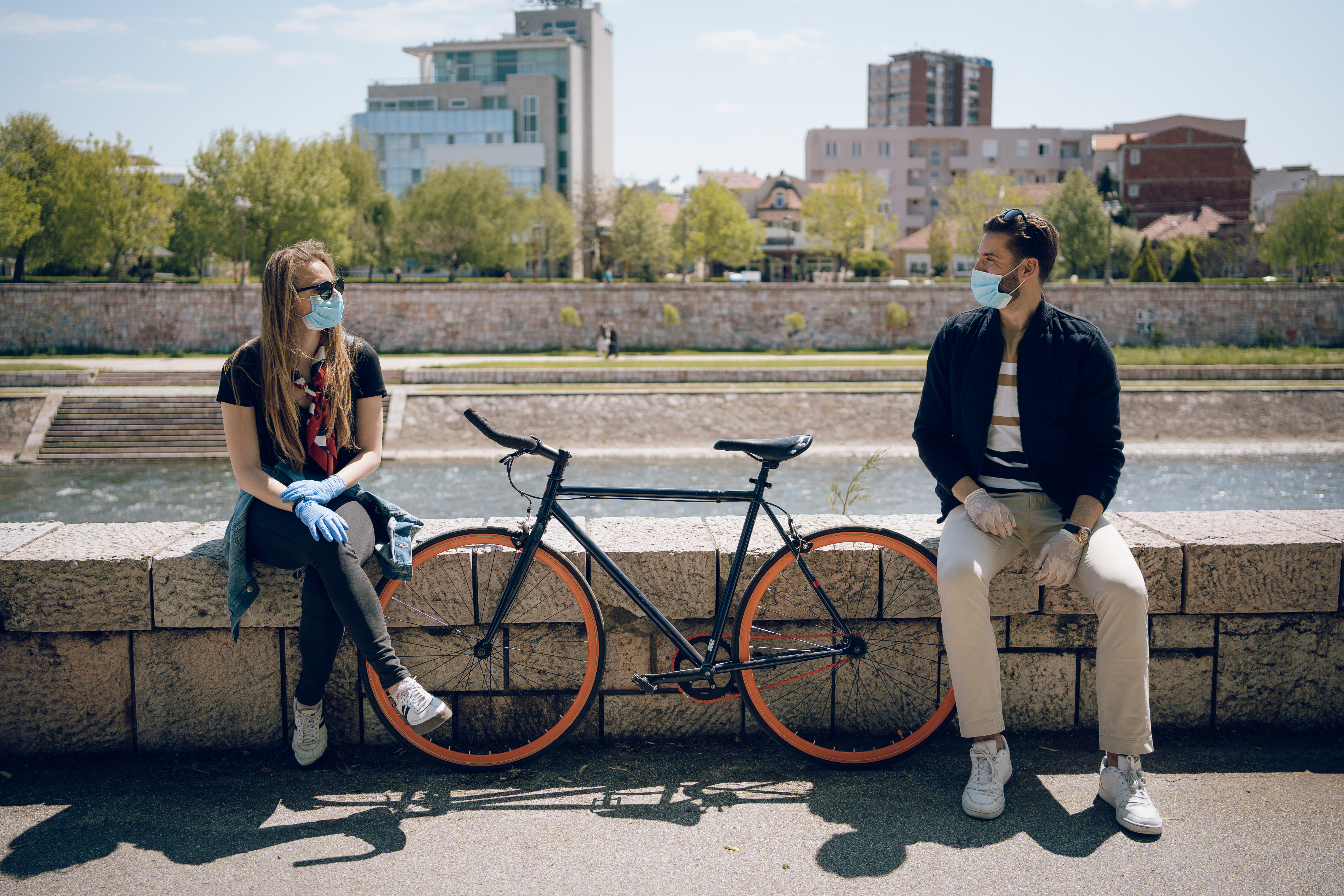 Young couple trying to maintain their relationship during a pandemic. They enjoy their love, applying all protection measures and wearing protective masks and gloves.