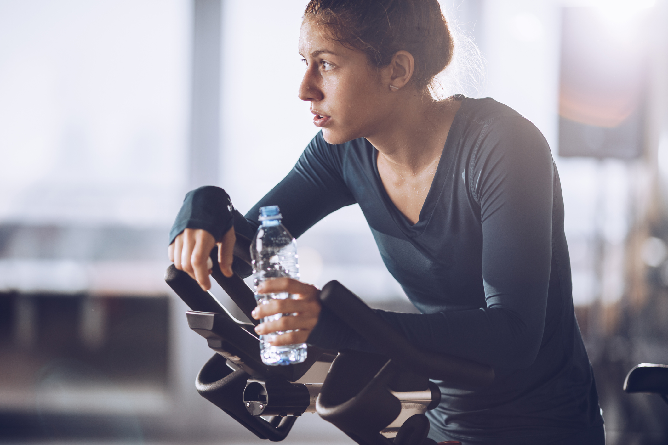 Tired sportswoman having a water break during exercising class in a health club.