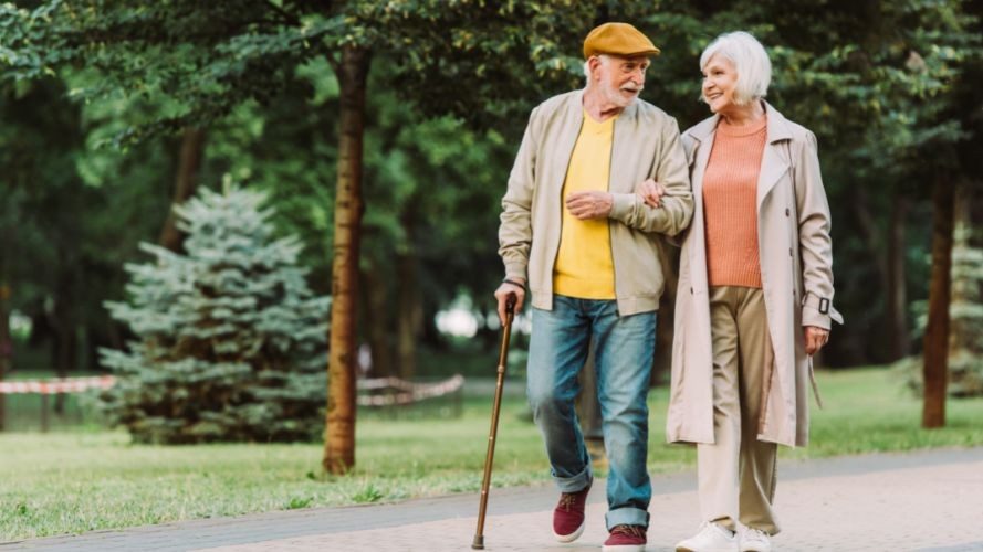 happy-senior-couple-walk-in-park-with-cane