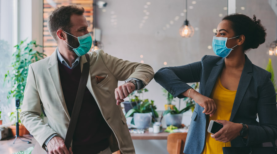 Colleagues in the office practicing alternative greeting to avoid handshakes during COVID-19 pandemic