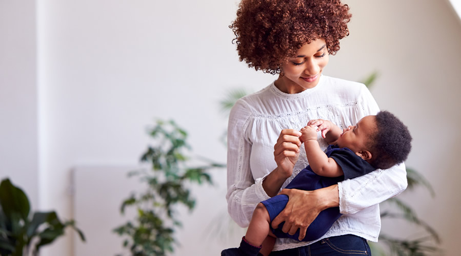 Loving Mother Holding Newborn Baby At Home In Loft Apartment