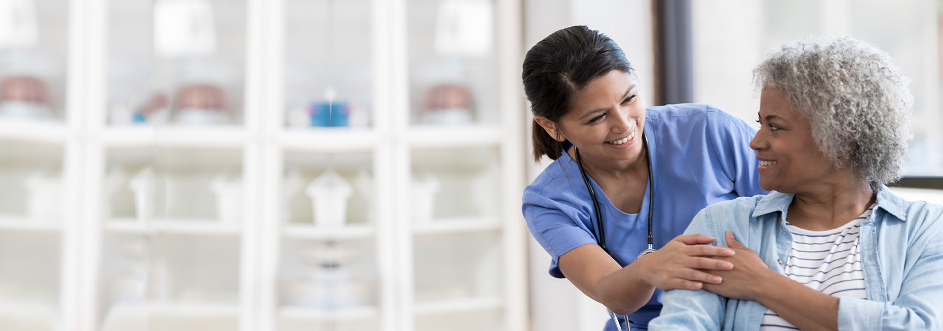 Caring nurse smiles at an African American senior female patient.