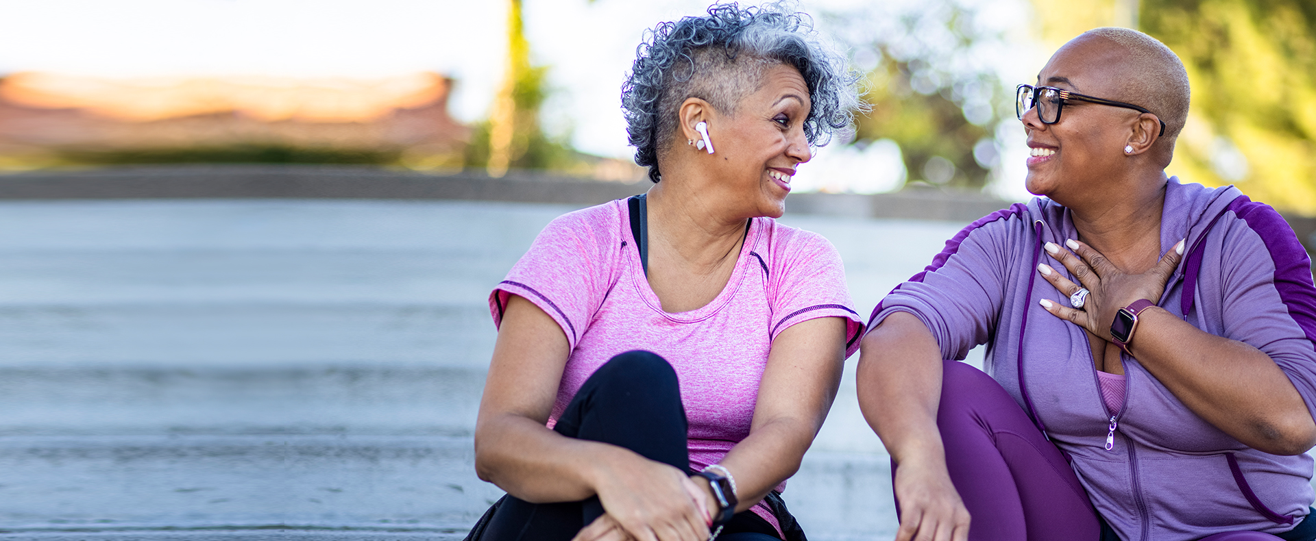 Two elderly African-American women sitting and talking after jogging in the park during women's health week