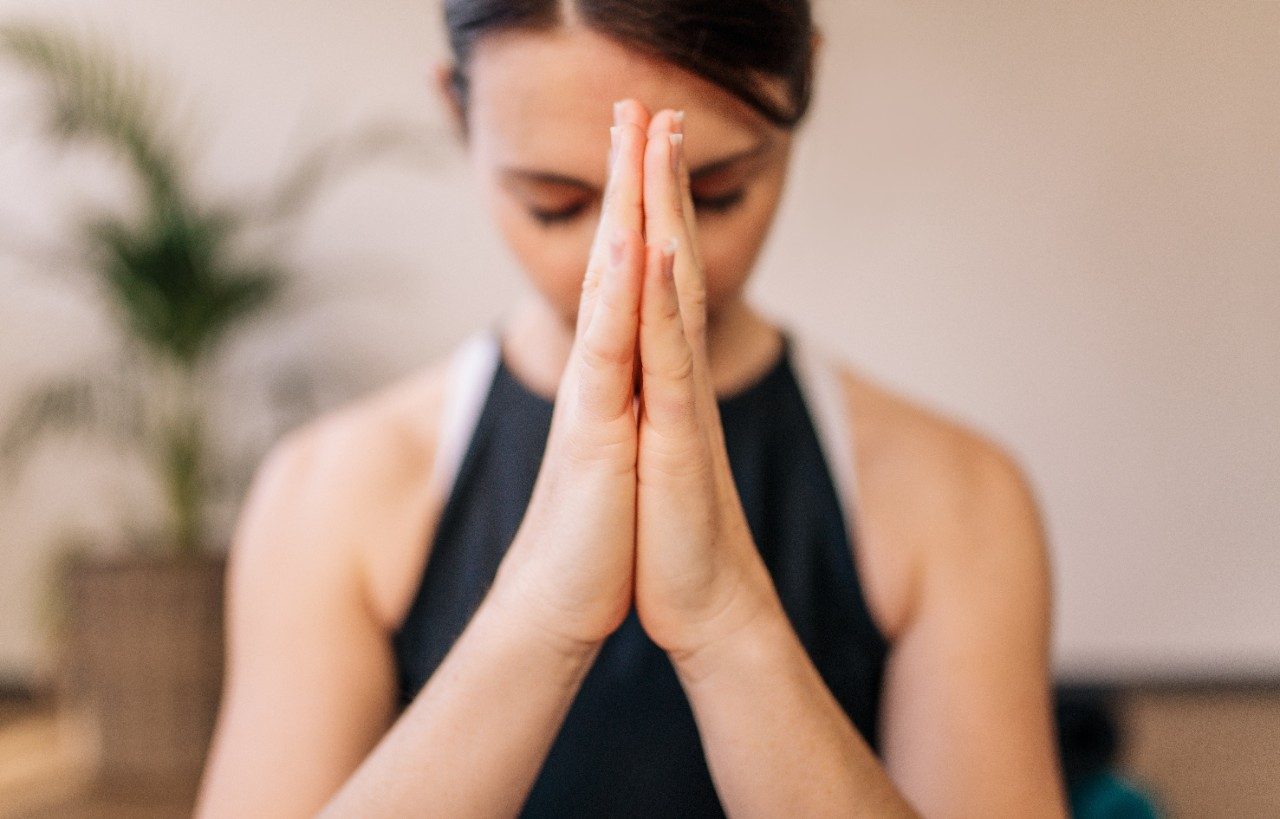 Close up of woman hands joined. Female meditating with her hands joined indoors. Namaste yoga pose, meditating, breathing and relaxing.