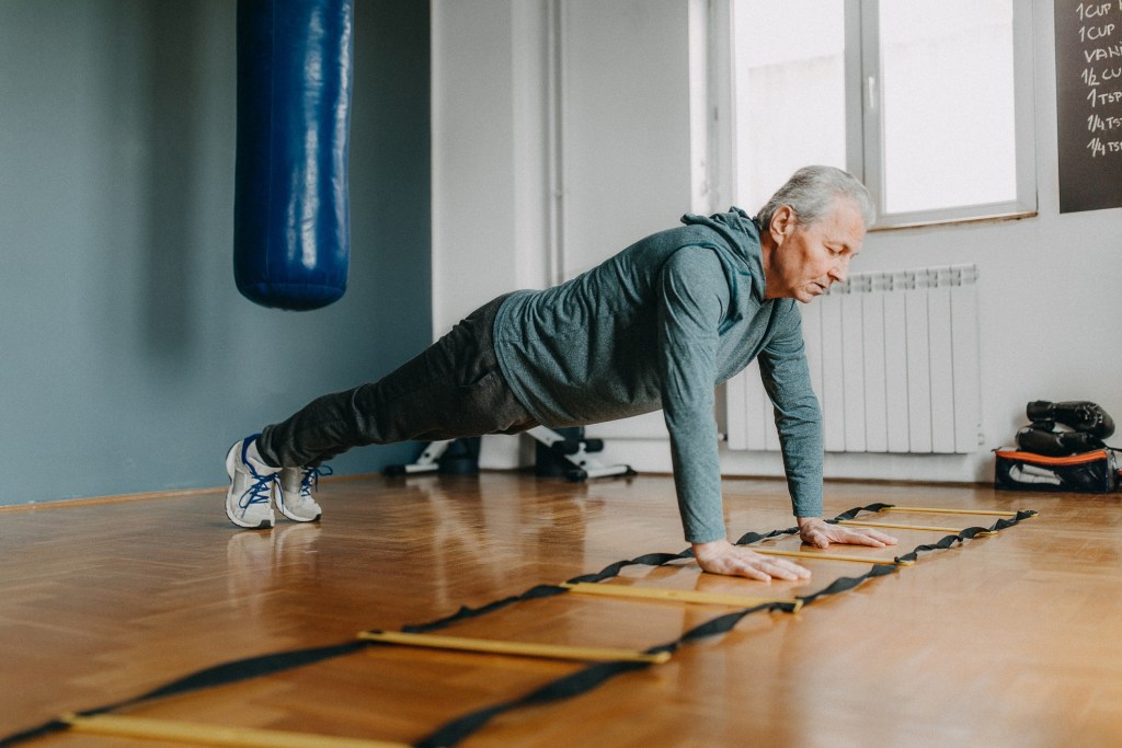 Senior man exercising with the assistance from young woman - personal trainer