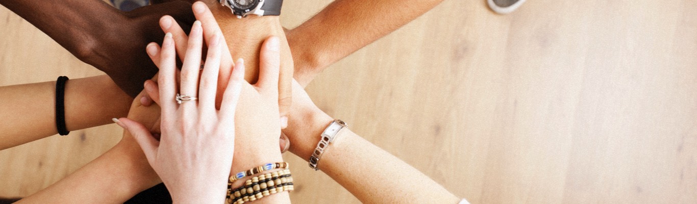 Stack of hands wearing bracelets and watches.