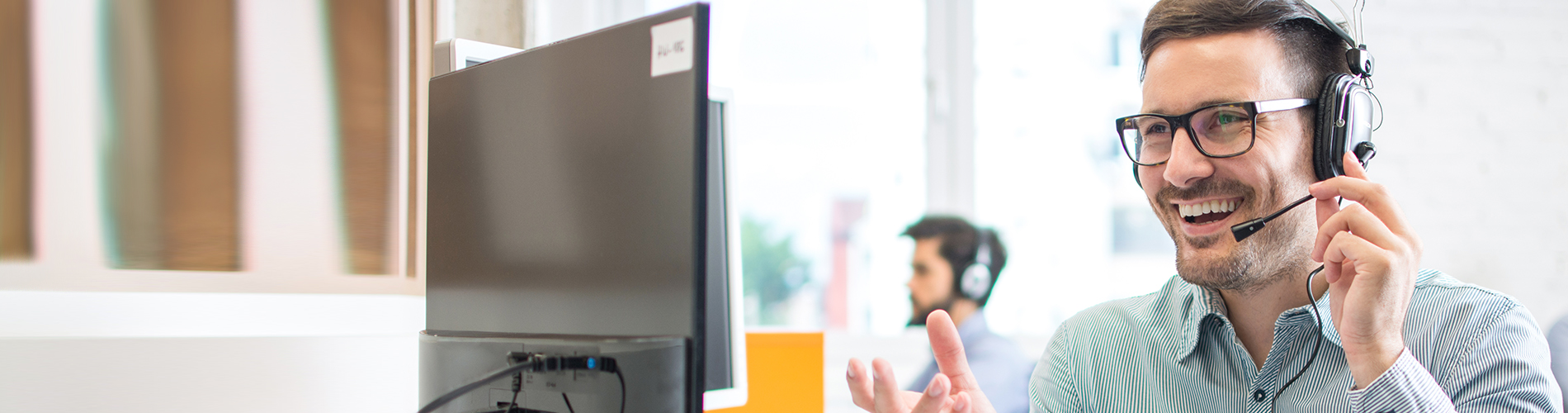 Man sitting in front of computer and talking in headphones