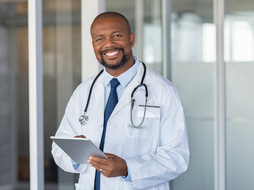 Young male doctor smiling and holding a clipboard