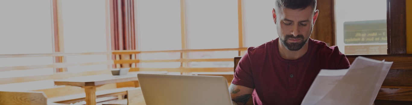 Man sitting in front of laptop looking at papers.