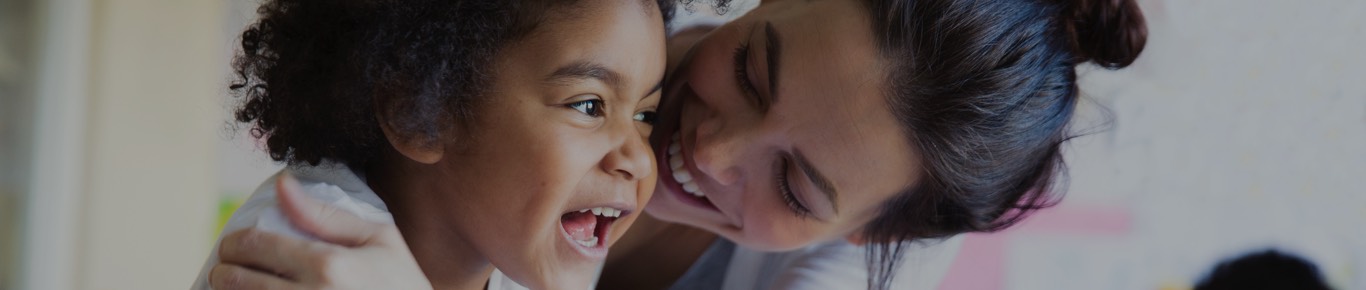 Woman hugging her smiling child from the side.