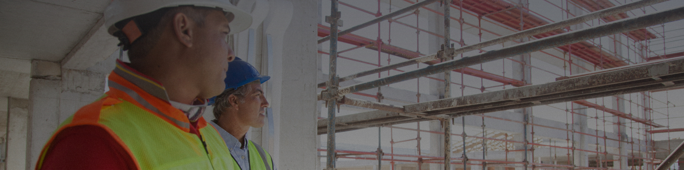 Two man in hard hats looking at construction site.