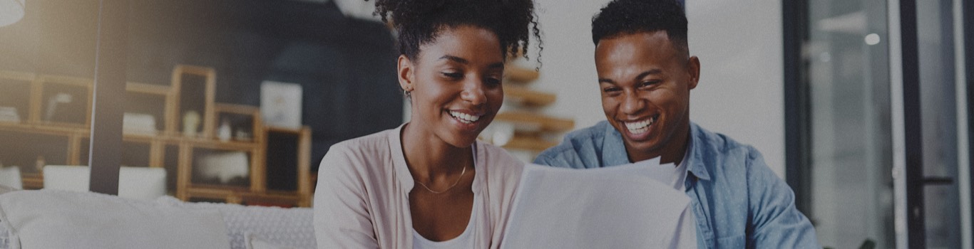 Couple smiling and looking at papers together.