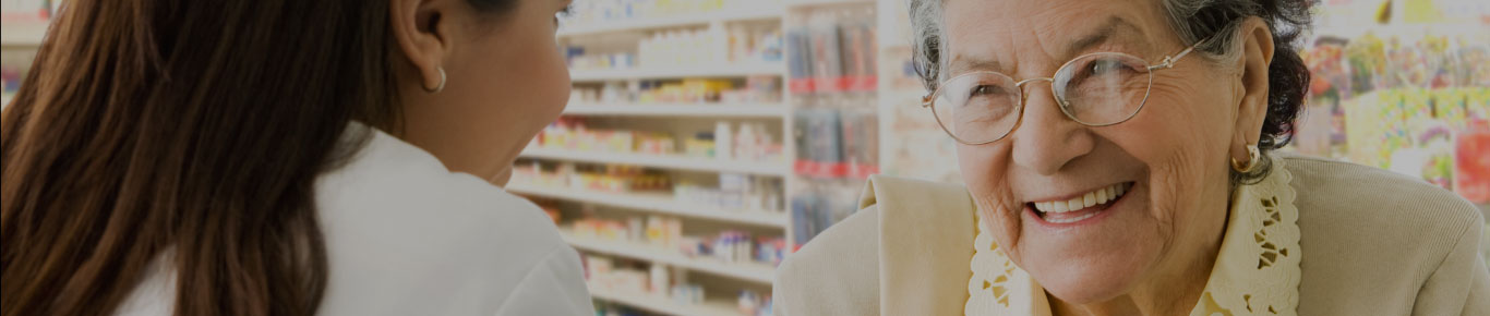 Older woman with glasses smiling at pharmacist.