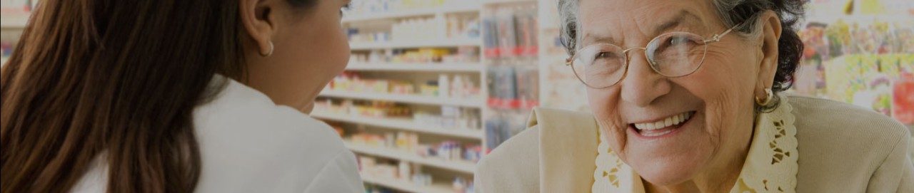 Older woman with glasses smiling at pharmacist.