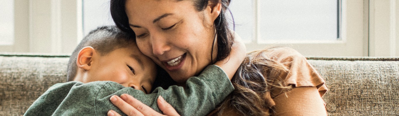 Woman cuddling with young son on the couch.