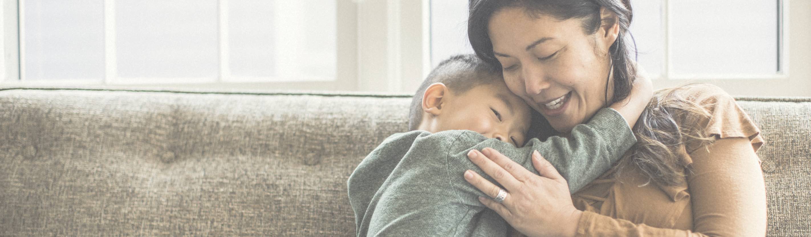 Woman hugging her son on the couch.