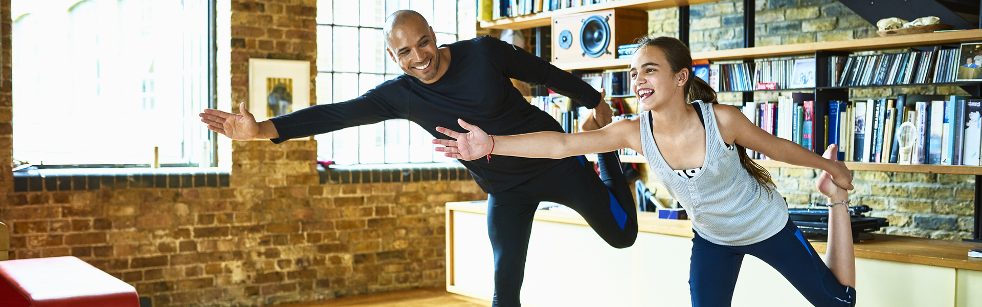 Father and daughter performing yoga stretches at home.