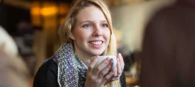 young adult woman having coffee and smiling