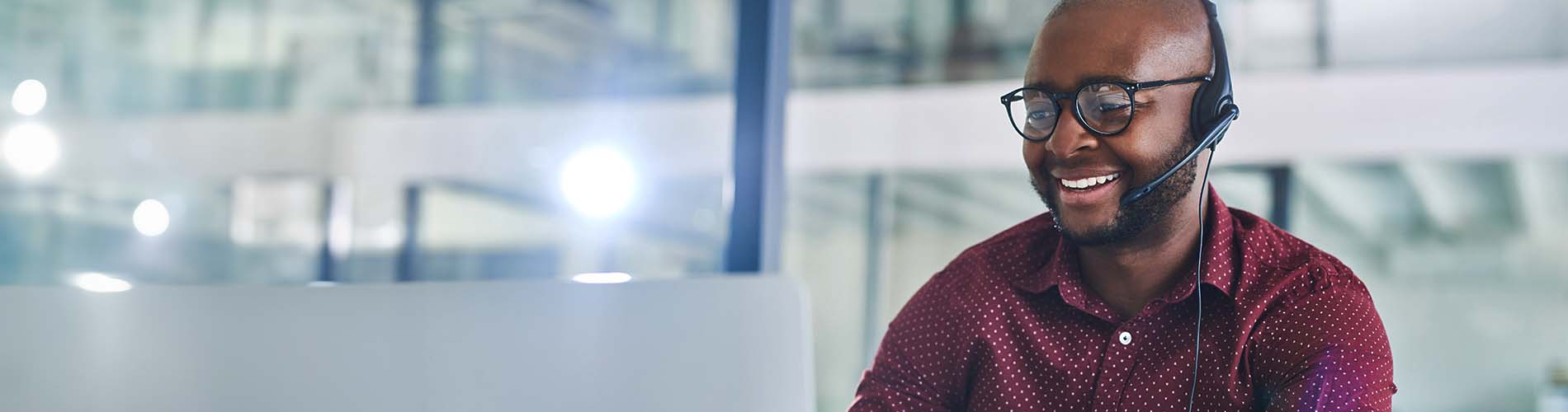 man with headset smiling at computer 