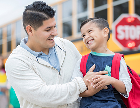 Dad smiles at his kindergarten age son before the boy goes to school