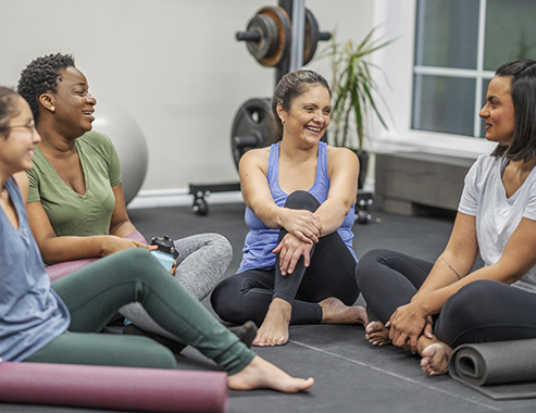 A small group of happy people sitting in a circle on yoga mats 