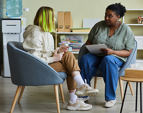 social worker talking to teenage girl and sitting on armchairs