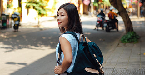 young asian female with backpack walking on street