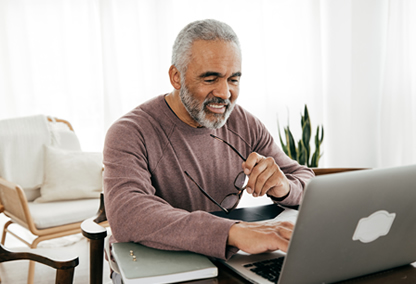 Senior man exploring essential health plan on computer at home