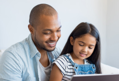 Young father and daughter smiling and looking at tablet