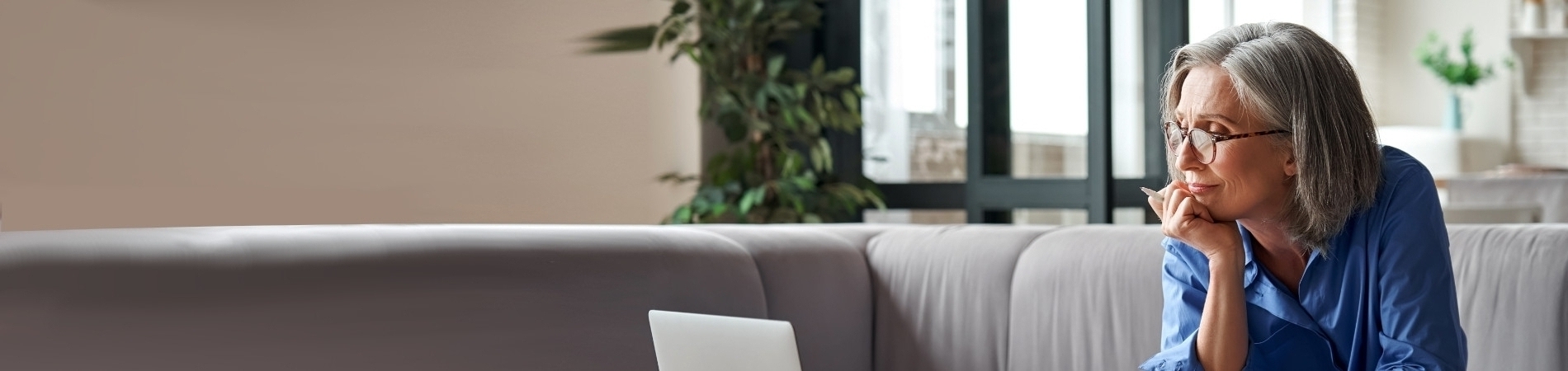 Older woman sitting on couch looking at a laptop