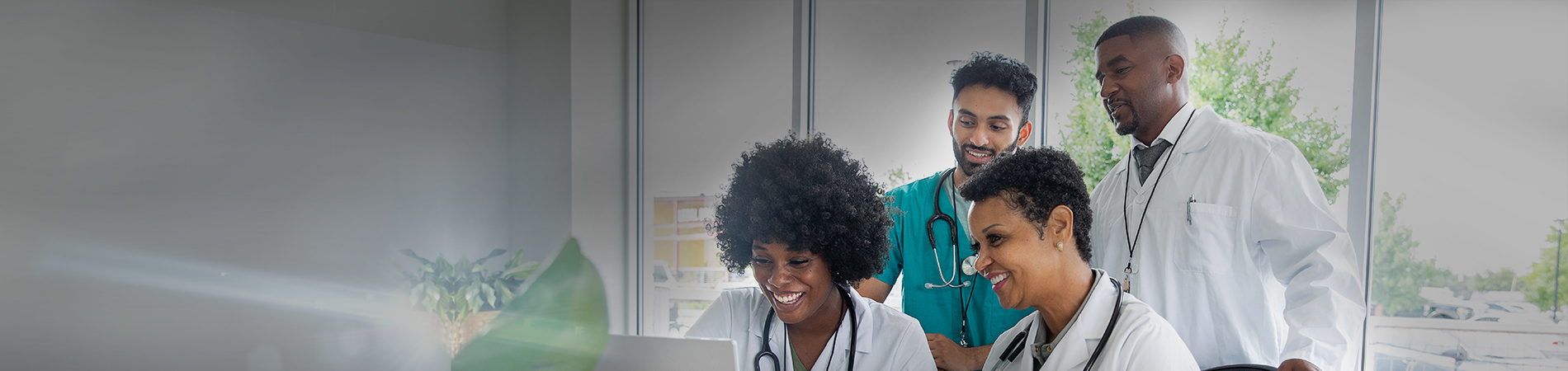 Group of happy healthcare providers looking at a computer in office