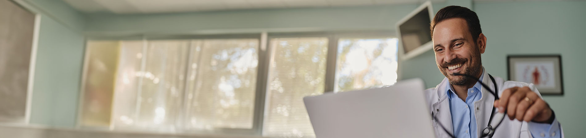 Happy male doctor  on a computer in the office at hospital.