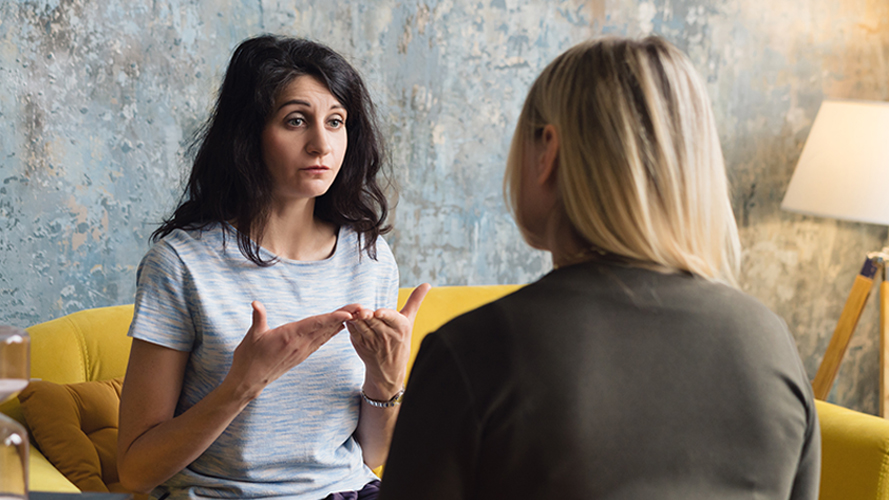 Woman psychologist talking to patient woman. Therapist's gestures. Female talking in coworking office