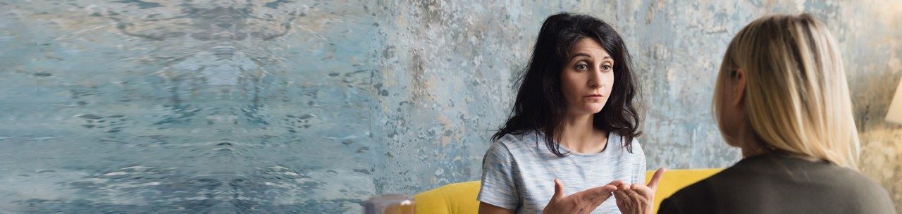 Woman psychologist talking to patient woman. Therapist's gestures. Female talking in coworking office