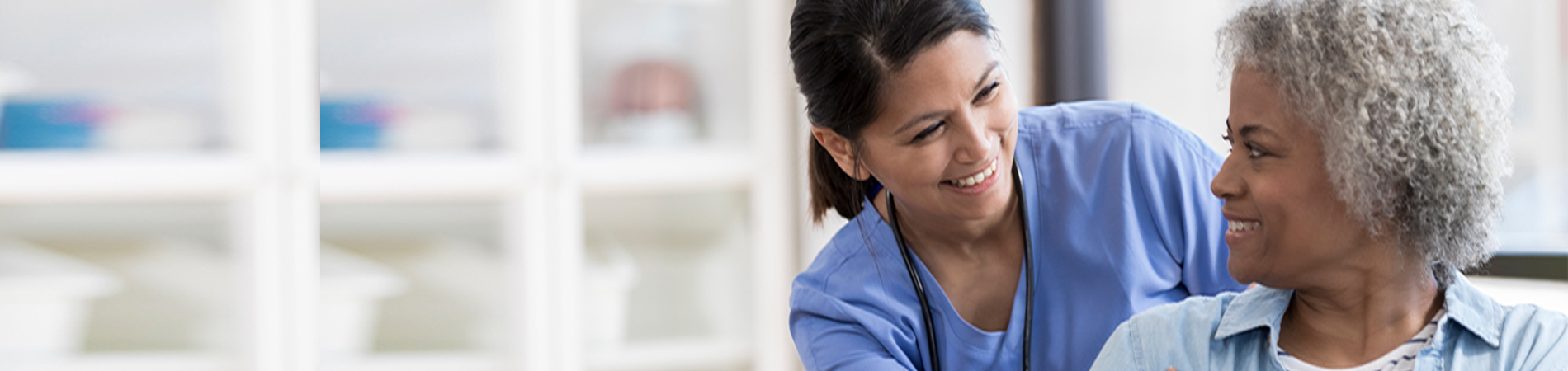 Caring nurse smiles at an African American senior female patient.