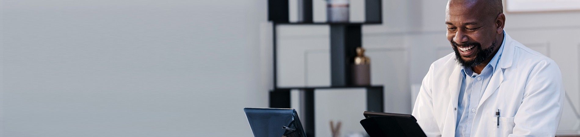 Male doctor smiling and looking at tablet