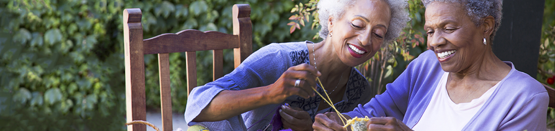 Two senior women knitting outdoors