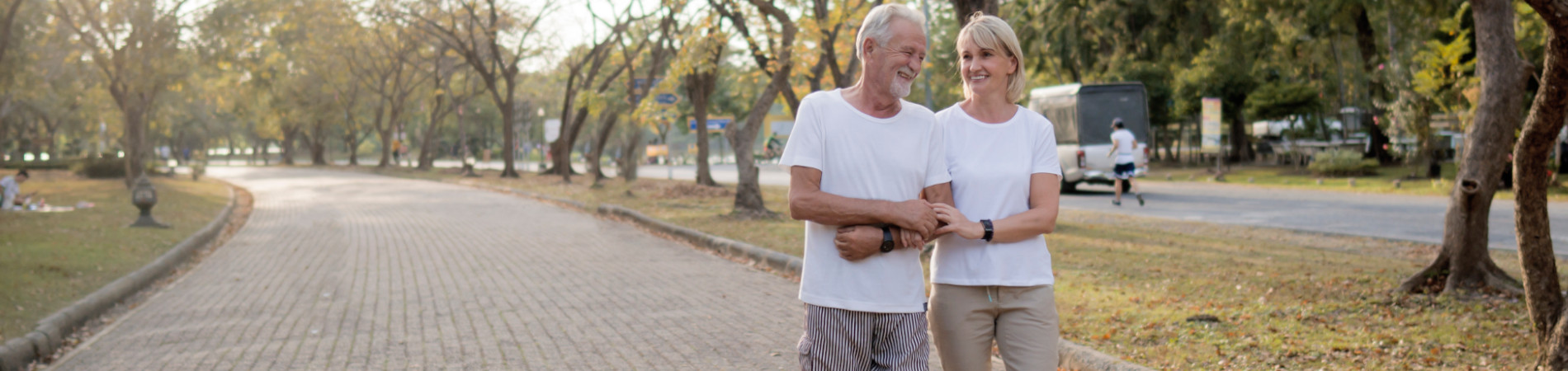 Older couple smiling and going on a walk in the park
