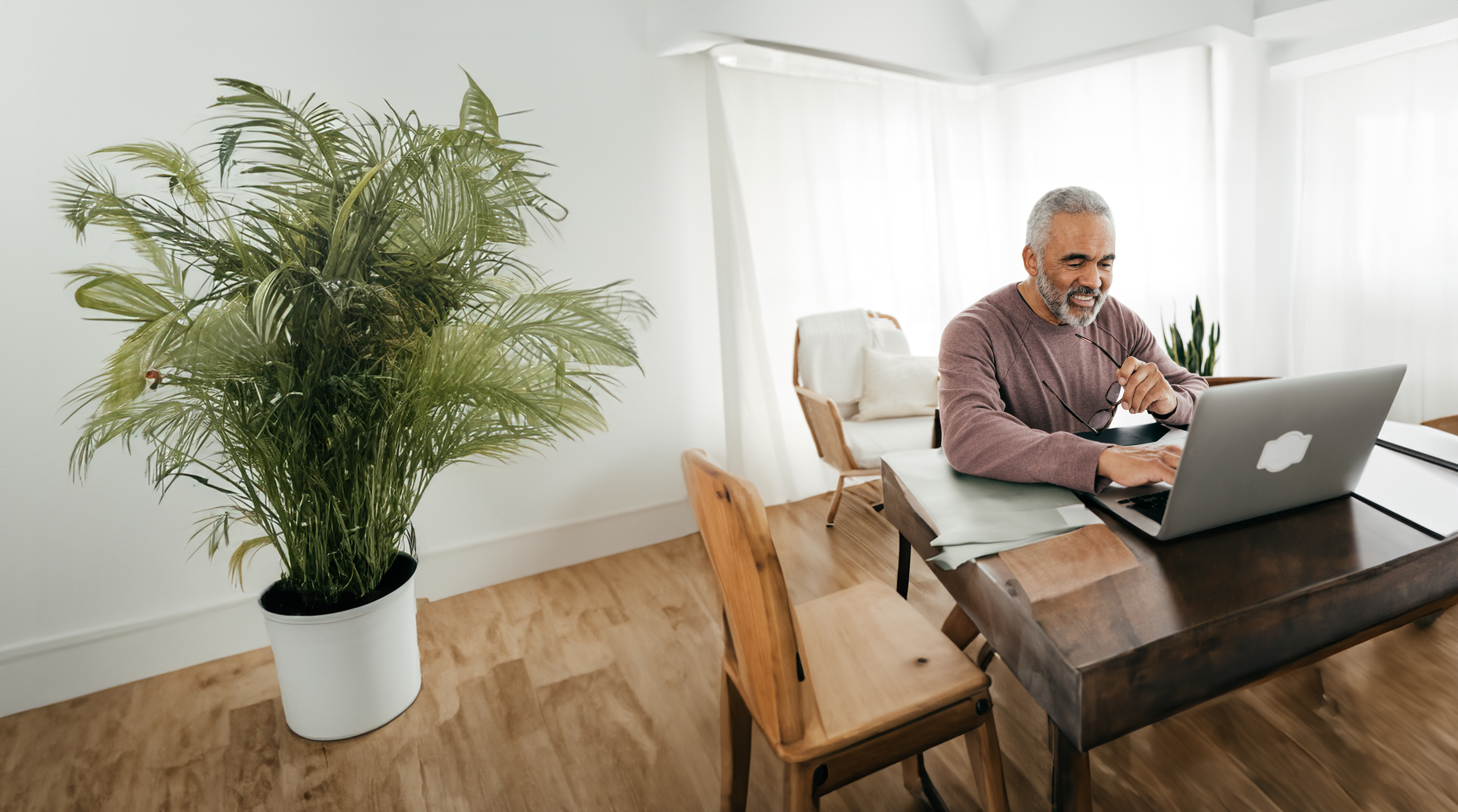 Senior men sitting at his desk at home looking at his computer.