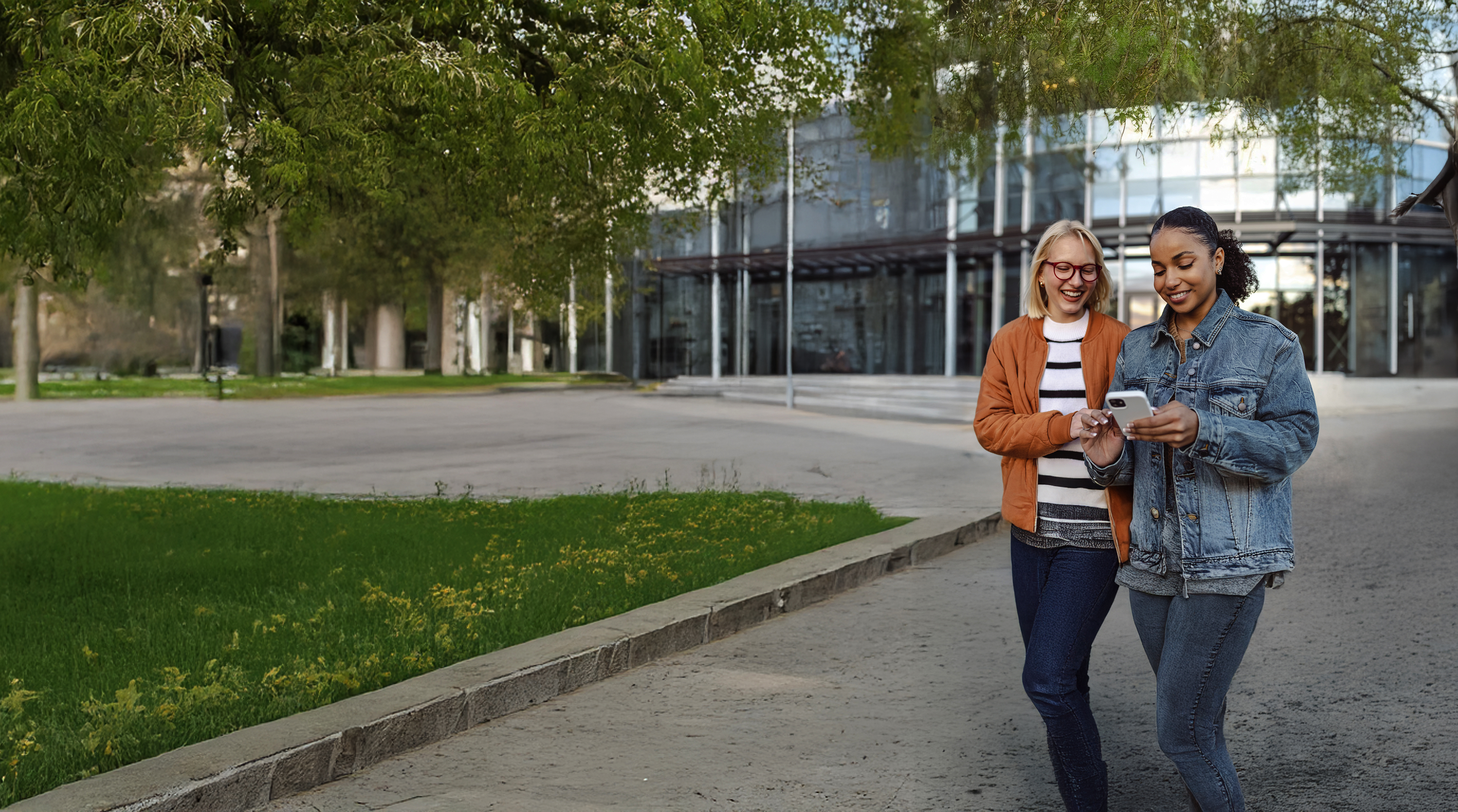 two adults smiling and looking at mobile device outside
